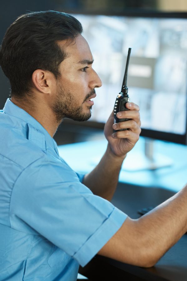 Control room, safety and security guard with a radio and computer screen for surveillance. Man and