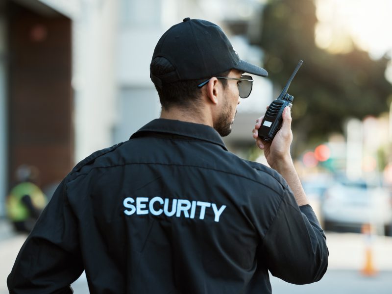 Radio, man and a security guard or safety officer outdoor on a city road for communication. Back of